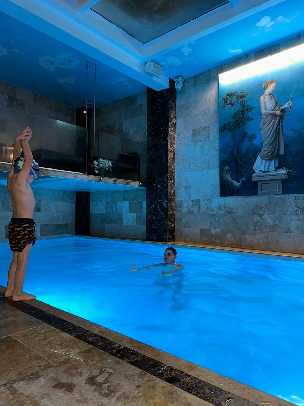 antrenor-in-piscina-si-baietel-care-se-pregateste-sa-sara-in-piscina-de-pe-marginea-piscinei